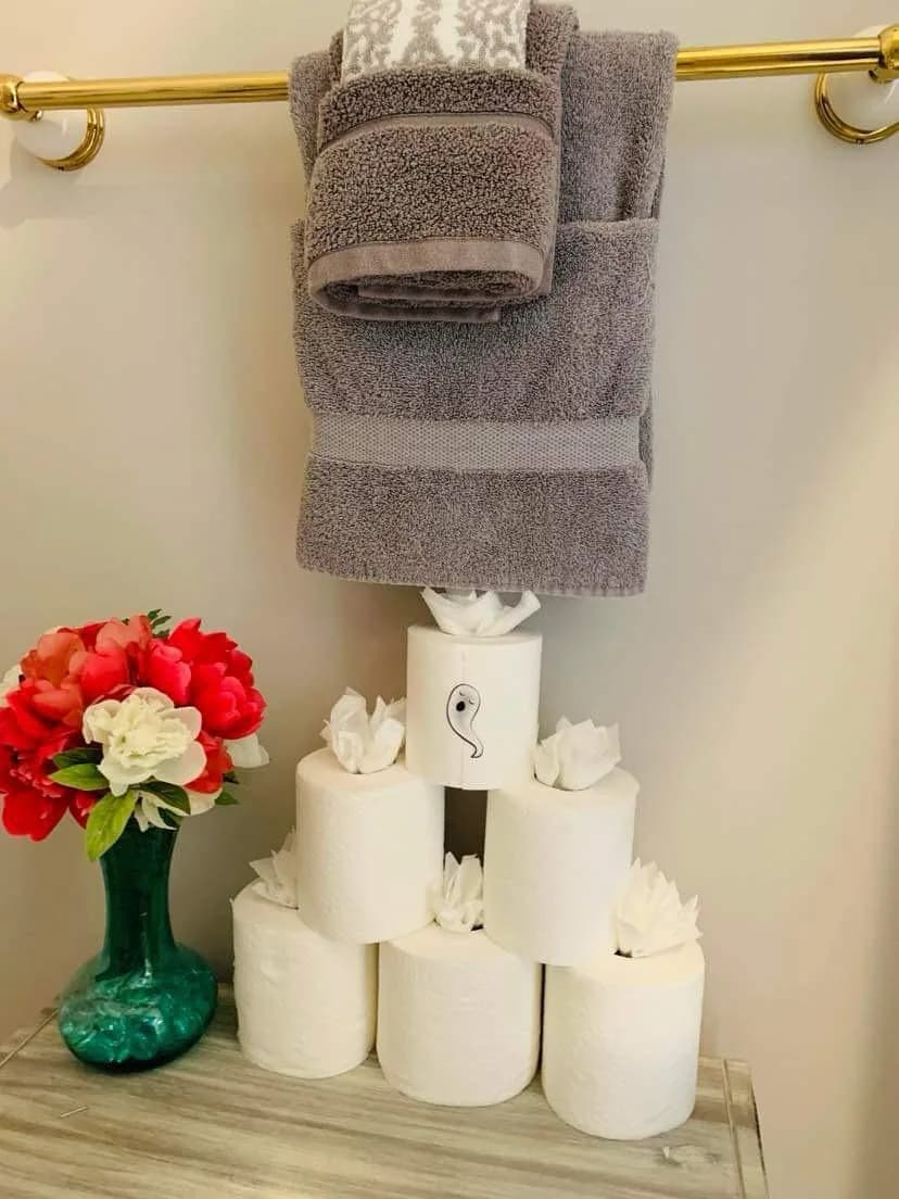 Bathroom finished with folded towels, stacked paper and fresh flowers by Dolane Cleaning Services